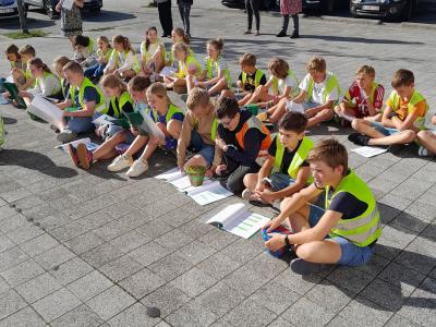 Kinderen, zittend op het dorpsplein, zingen en trommelen voor de vrede.